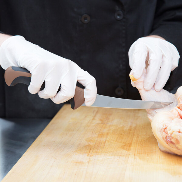 A person in white gloves using a Mercer Culinary brown handled boning knife to cut a piece of meat.