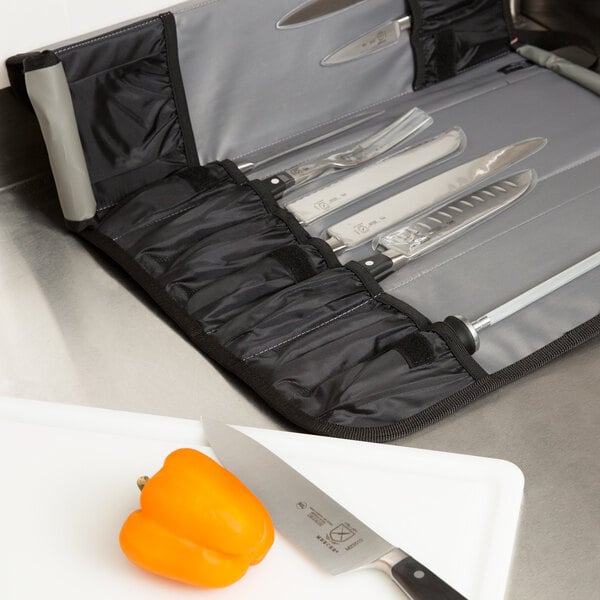 A Mercer Culinary Renaissance knife case set on a cutting board with a knife next to a bell pepper.