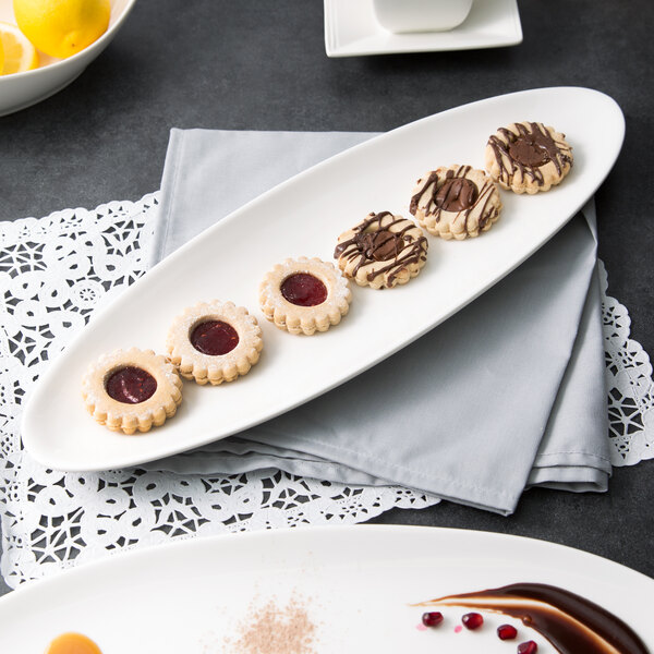 A white porcelain leaf platter with cookies on a table.