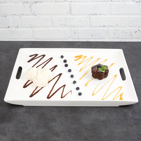 A white rectangular porcelain platter with brownies and blueberries on it.