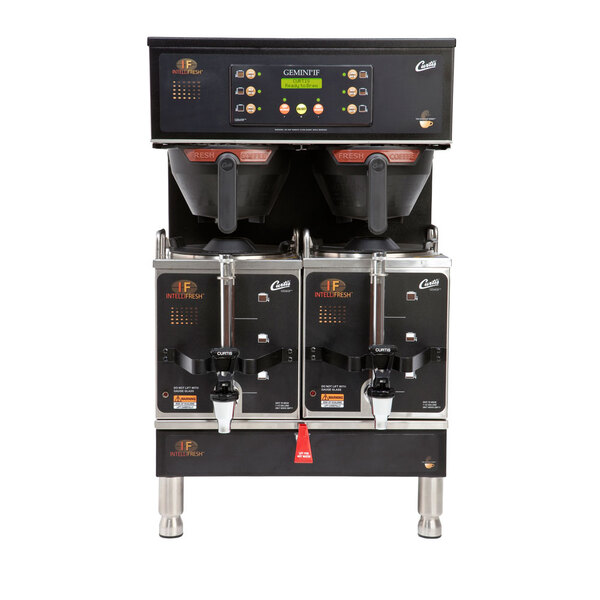 A black Curtis commercial coffee machine with two coffee pots on top and green screen panel.