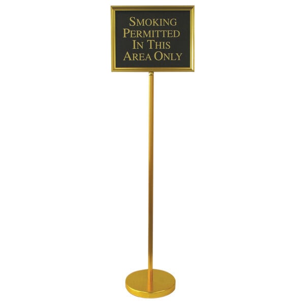 A gold Aarco hostess/teller sign on a long yellow pole with white text.