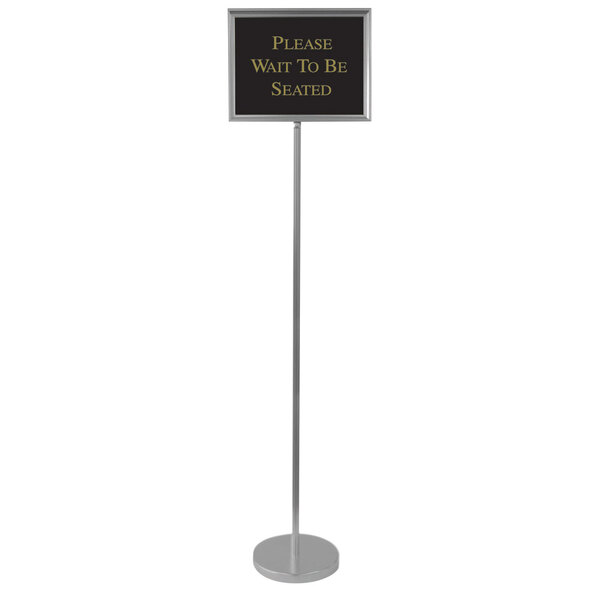 An aluminum pole with a black sign that has gold text on it.