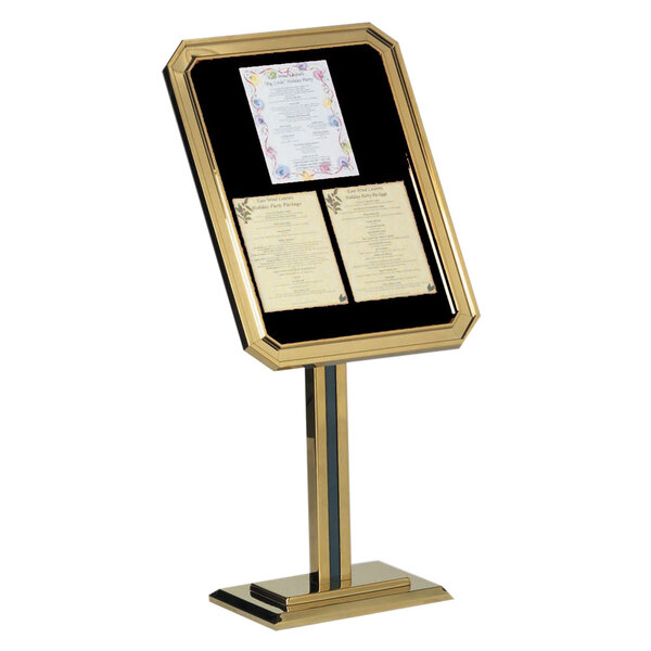 A gold and black Aarco ornamental sign stand with a menu on a table.