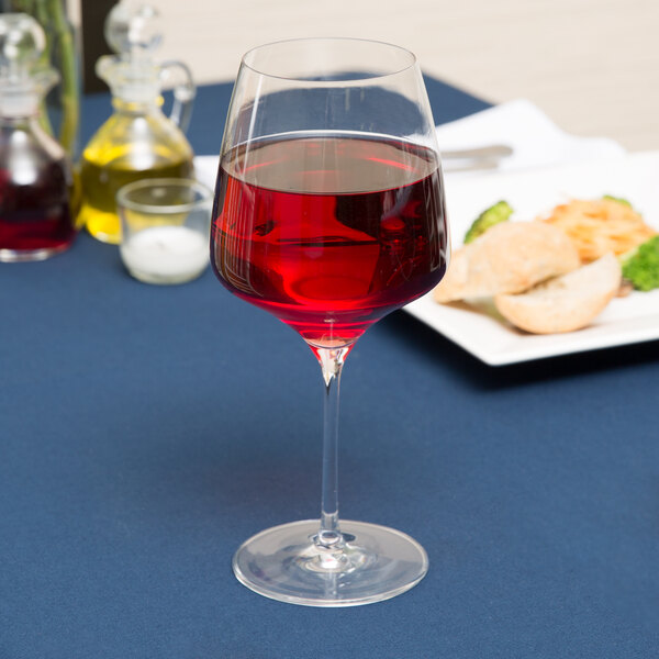 A Stolzle burgundy wine glass filled with red wine on a table.