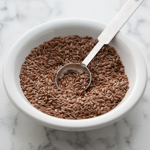 A bowl of Regal brown flax seeds with a spoon.