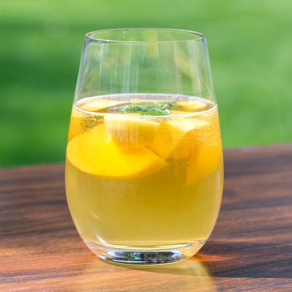 A Stolzle stemless wine glass filled with yellow liquid and slices of fruit.