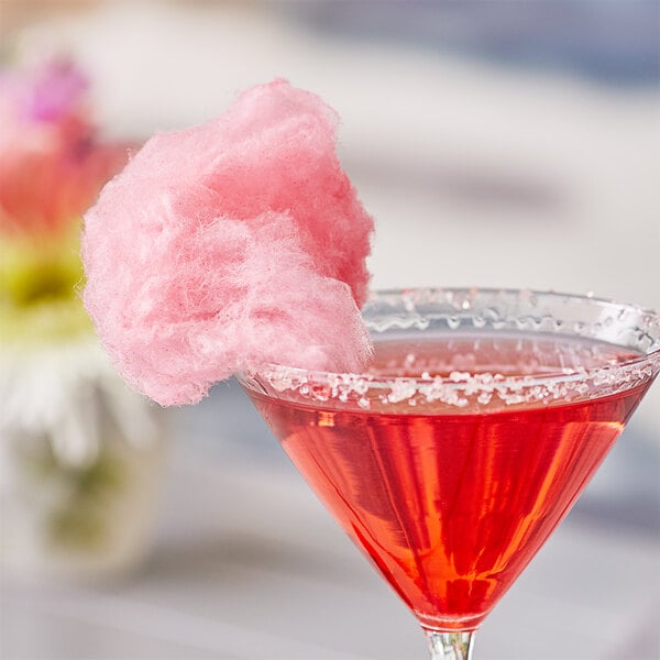A pink drink with a cotton candy in it made with Great Western red cherry cotton candy floss sugar.