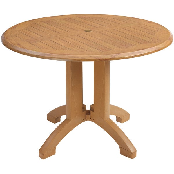 A Grosfillex Winston teak pedestal table with a round top and legs.