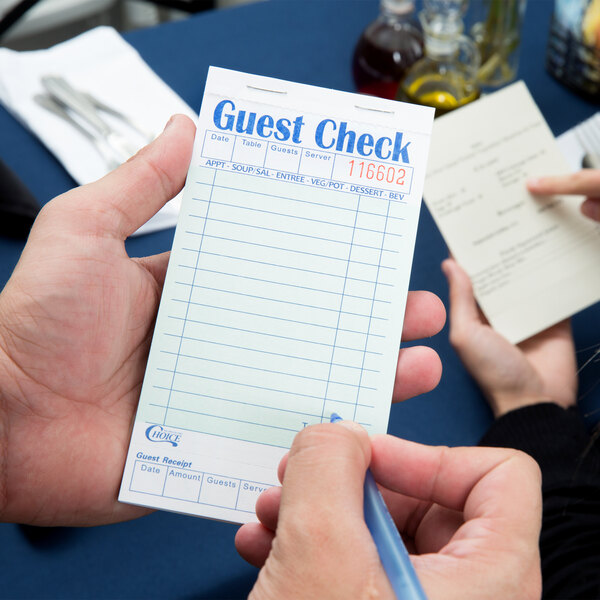 A person using a green and white Choice guest check to write on.