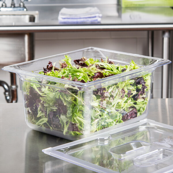 A Vollrath clear polycarbonate food pan with green and red lettuce in it.