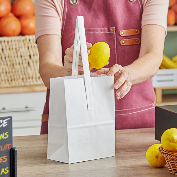 A woman holding a white Choice paper bag with lemons.