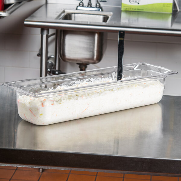 A Vollrath clear polycarbonate food pan on a counter full of food.