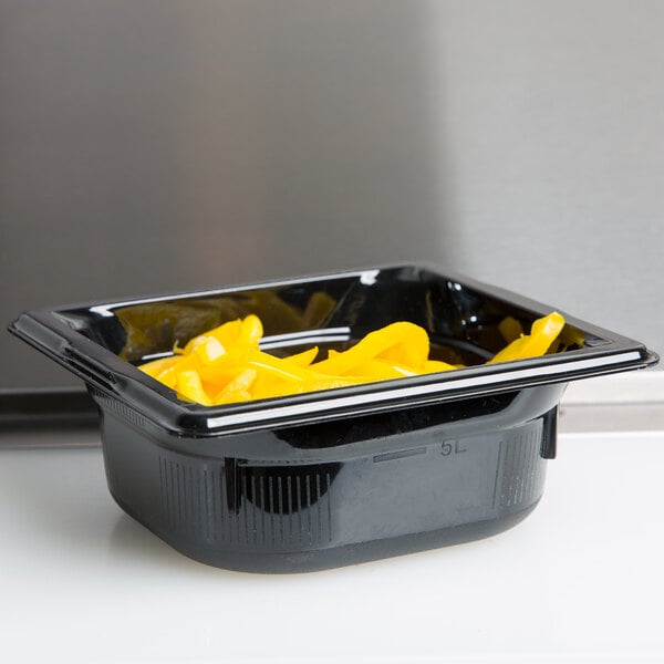 A black Vollrath 1/6 size polycarbonate food pan with yellow food inside.