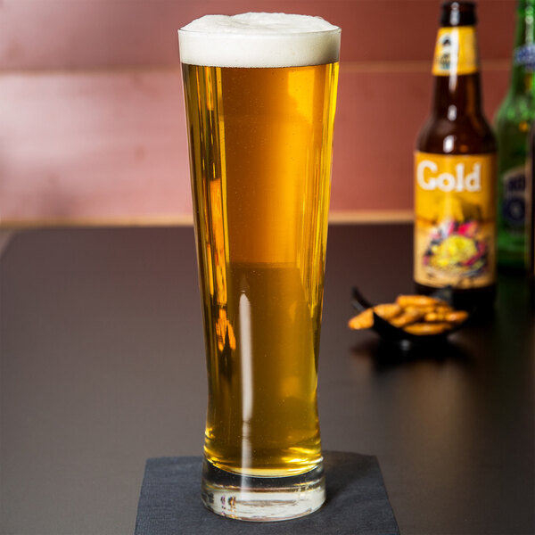 A Libbey Pinnacle pilsner glass full of beer on a table.