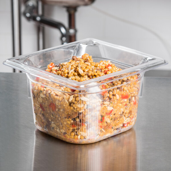A Vollrath clear polycarbonate food pan with food inside on a counter.