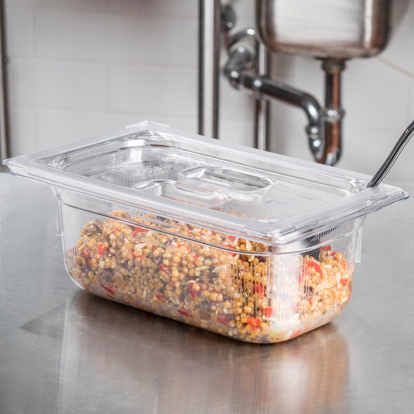 A Vollrath clear polycarbonate food pan with food in it on a counter.