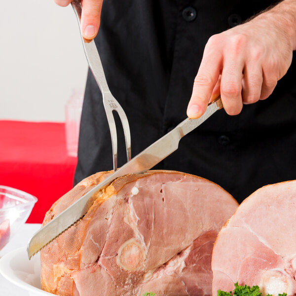 A person using an American Metalcraft hammered stainless steel knife to cut ham.