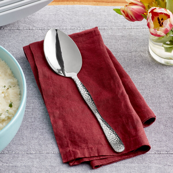 An American Metalcraft hammered stainless steel spoon on a red napkin next to a bowl of rice.