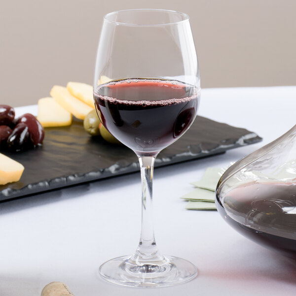 A Stolzle Weinland wine glass filled with red wine next to a tray of cheese and olives.