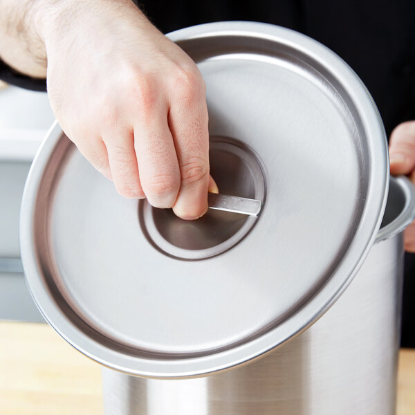 A person's hand opening a Vollrath stainless steel Bain Marie cover.