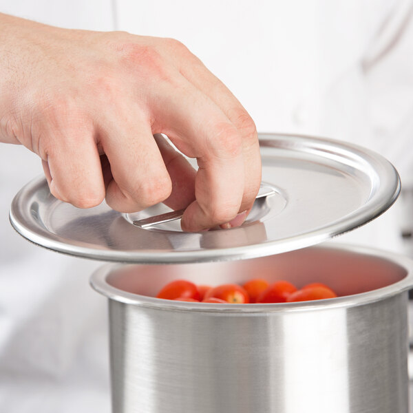 A person using a Vollrath Stainless Steel Bain Marie Cover to cover a pot of tomatoes.