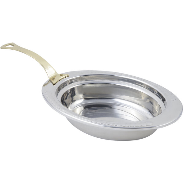 A silver stainless steel Bon Chef oval food pan with a long brass handle decorated with a laurel design.