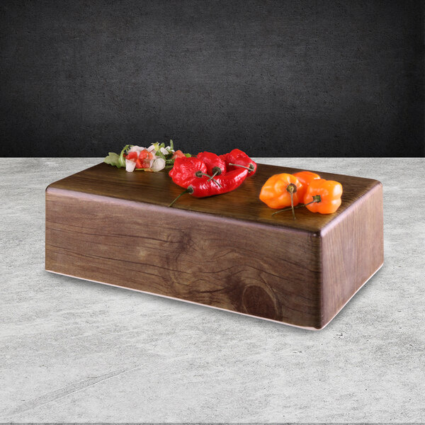A rectangular faux walnut melamine modular riser with peppers on it.