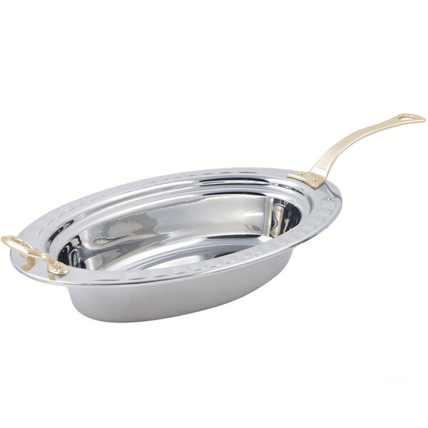 A silver stainless steel oval food pan with a long brass handle.