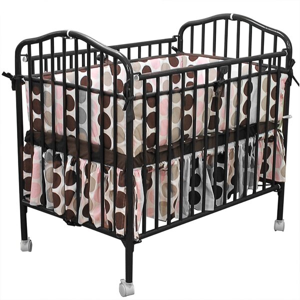 A black metal L.A. Baby folding crib with a pink and brown polka dot sheet.