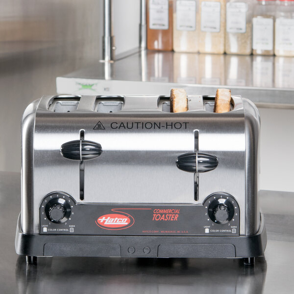 A Hatco commercial toaster on a brown counter with a white sign above it.