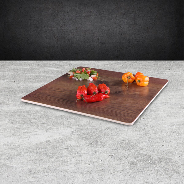 An Elite Global Solutions faux walnut melamine serving board with red peppers on it.