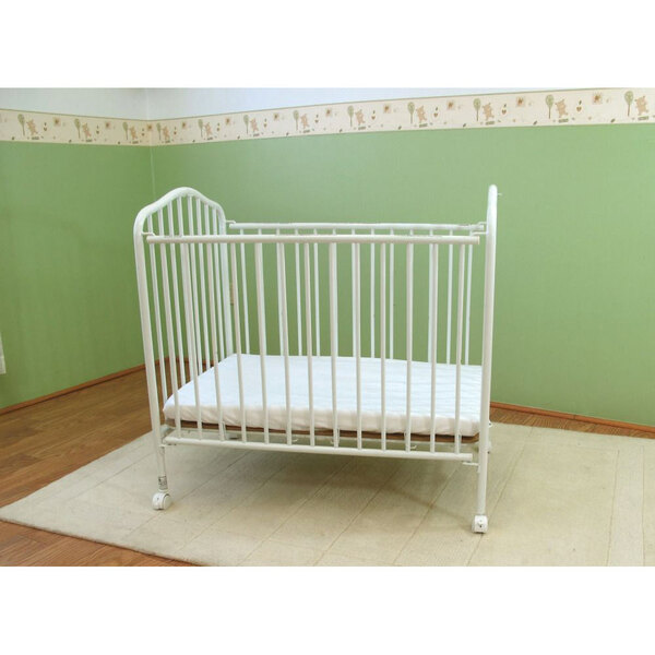 A white metal L.A. Baby folding crib with a white sheet on a mattress.