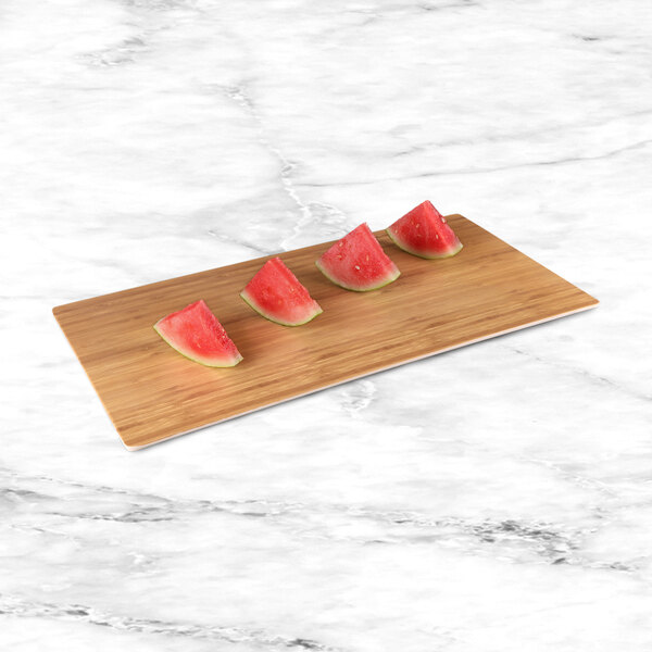 Watermelon slices on a rectangular faux bamboo melamine serving board.