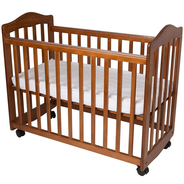 A pecan colored wooden cradle with a white mattress in it.