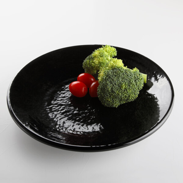 A black Elite Global Solutions round plate with broccoli and tomatoes on it.