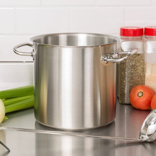 A silver Vollrath stainless steel stock pot on a counter with green celery inside.
