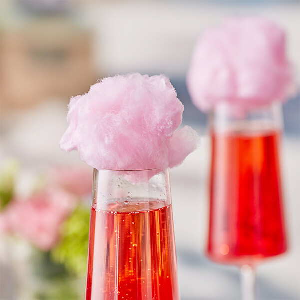 A glass of pink liquid with a pink cotton candy garnish.