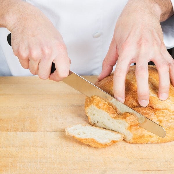 A person using a Victorinox curved serrated bread knife to cut bread.