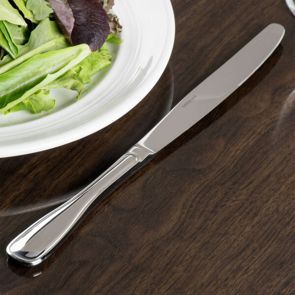 A plate of salad with a Oneida Stanford stainless steel dinner knife.