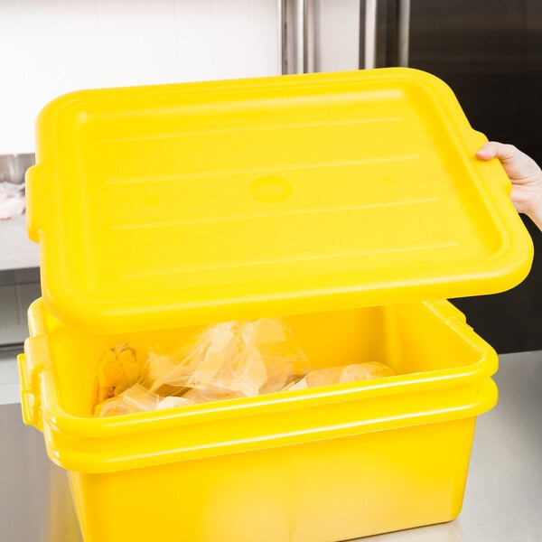 A hand holding a yellow Vollrath Traex food storage box lid over a yellow container.