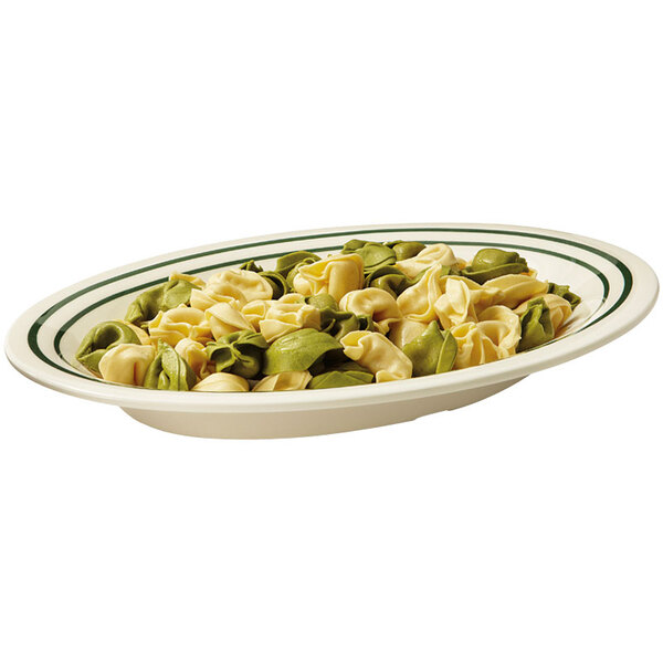 An oval platter of tortellini with green and white stripes.