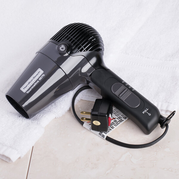 A black Hamilton Beach hair dryer on a white towel.