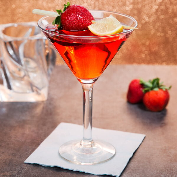 A Libbey Salud Grande Martini glass with a red cocktail garnished with strawberries and lemon slices.