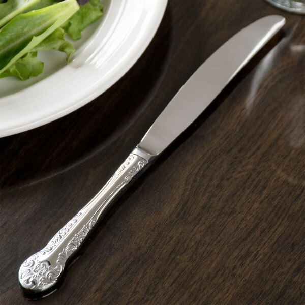 A Oneida Rosewood stainless steel dinner knife on a plate.