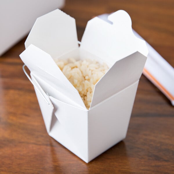A white Fold-Pak Chinese take-out container filled with rice on a table.