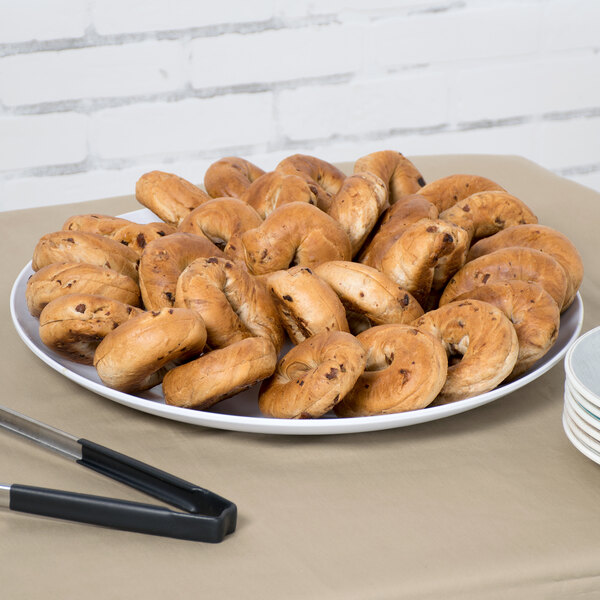 A white Siciliano display platter with a pile of bagels on a table.