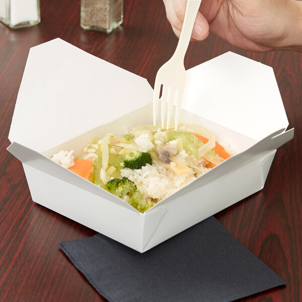 A hand holding a plastic fork over a white Fold-Pak Bio-Pak take-out box of food.