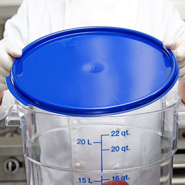 A chef holding a blue Carlisle food storage container lid.