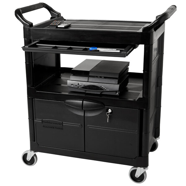 A black Rubbermaid utility cart with lockable doors and a sliding drawer on a counter.